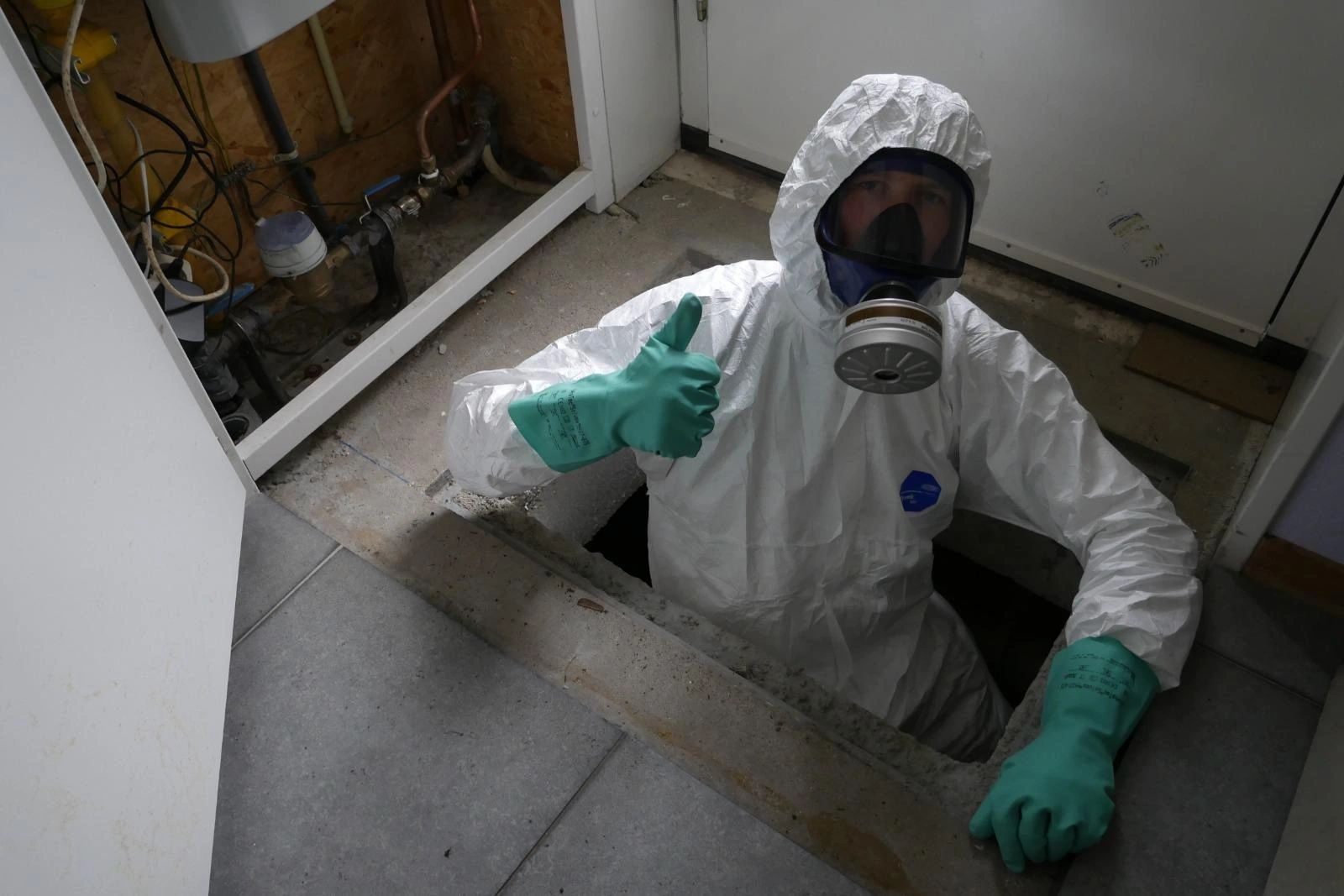 Medewerker in beschermende uitrusting werkt vanuit de kruipruimte